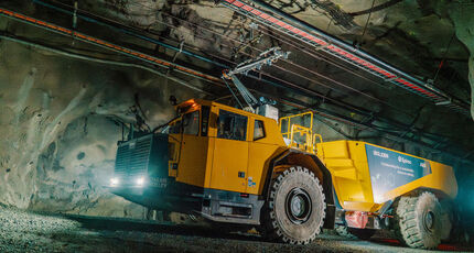 Side view of an electric Epiroc underground mine truck connected to a trolley.