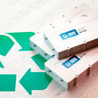 Three white lithium-ion batteries beside a green recycling symbol.