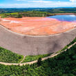 A large, rock-clad earthen dam holds back mining waste and water.