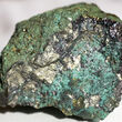 Rock sample with metallic gold mineralization coated with green copper oxides.