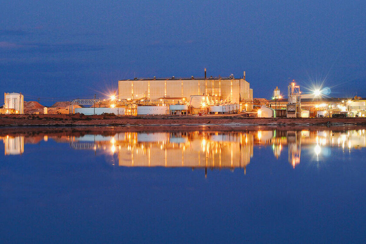 Lights from Energy Metals’ White Mesa Mill reflect off a pond at night.