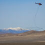 Helicopter carrying a large oval antenna over a desert region in Nevada.