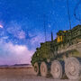 Night vision image of six-wheeled army vehicle under the Milky Way.