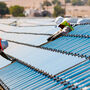 Workers install First Solar thin-film panels in a desert setting.