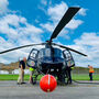 A helicopter equipped with geophysical survey equipment prepares for flight.