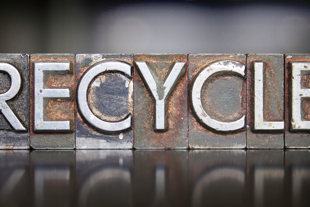 The word recycle stamped in all capital letters on tarnished steel blocks.