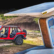 2023 Jeep Wrangler 4xe plugged into a solar charger in a rural setting.