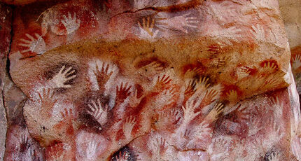 Stenciled outlines of human hands on cave walls.