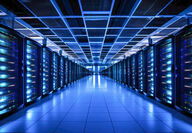 Stacks of servers in a dark-lit, blue-colored data center.