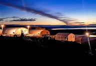 A colorful sunset behind commercial Quonset tents at graphite project in Alaska.