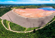 Massive earthen dam holds back red mud tailings at aluminum mine in Brazil.