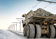 A mining truck being pulled up a snowy slope by an overhead trolley.