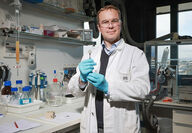 Swiss scientist holds artificial photosynthesis device for making hydrogen fuel.