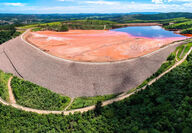 A large, rock-clad earthen dam holds back mining waste and water.