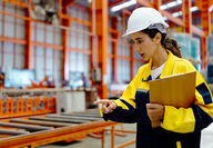Young female worker with hard hat and PPE in a warehouse setting.