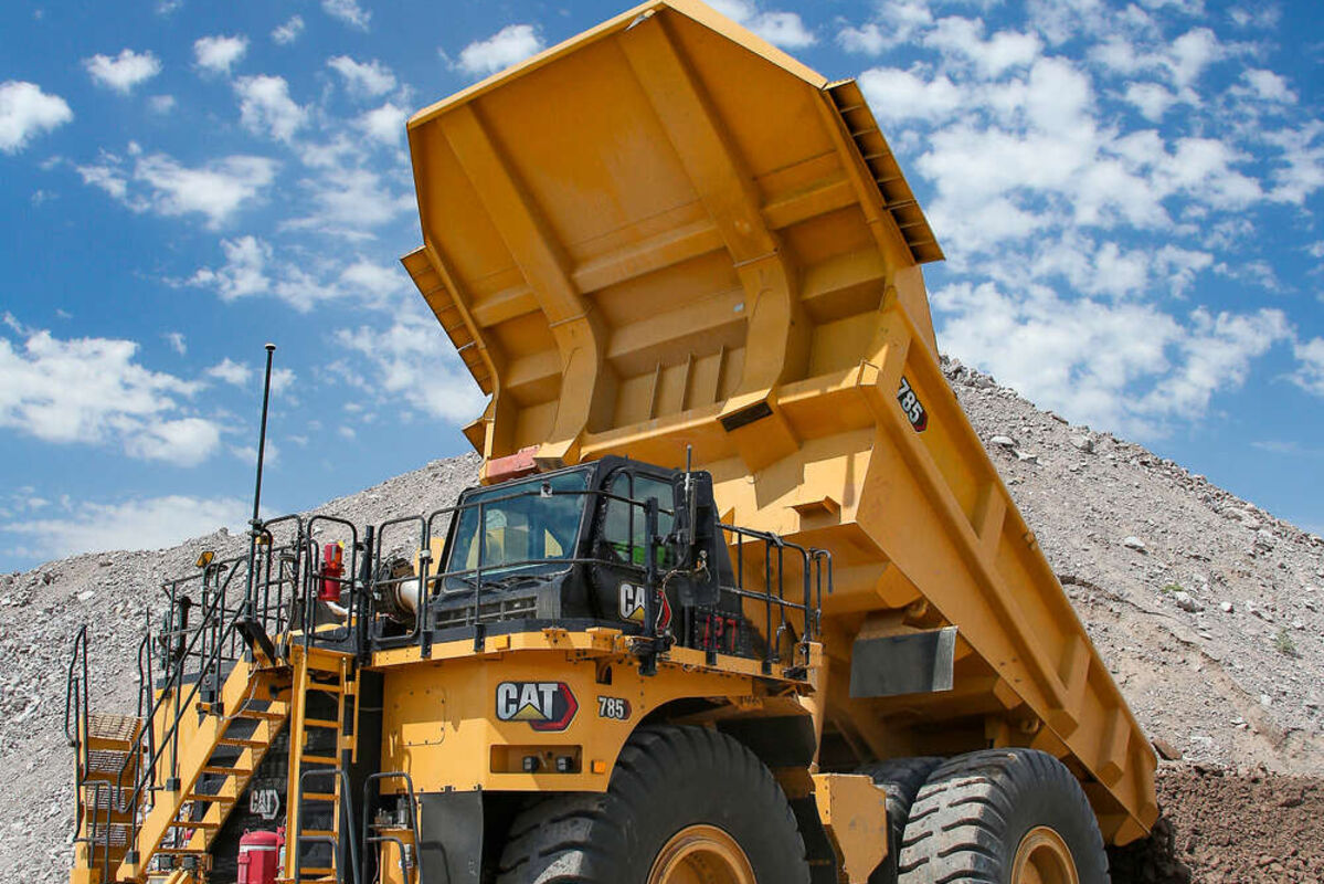 Cat 785 mining haul truck dumping material at a mine site.