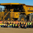 Cat 793 Electric mining truck towers over more than 50 people posed for a photo.