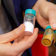 Man holding small vials of various rare earths processed with ISR technology.