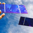Hands holding small thin film solar cell panels.