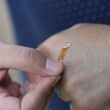A strip of mesoporous gold film being applied to the back of a hand.