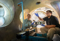Daoru Han and Jacob Ortega discuss space inside plasma vacuum chamber.