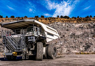 A two-story-tall white Liebherr T 264 truck parked in a mine pit.