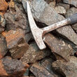 A rock hammer laying atop a pile of rare earths enriched carbonatites.