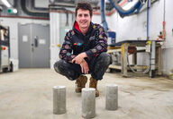 An RMIT researcher with three columns of concrete produced with PPE.
