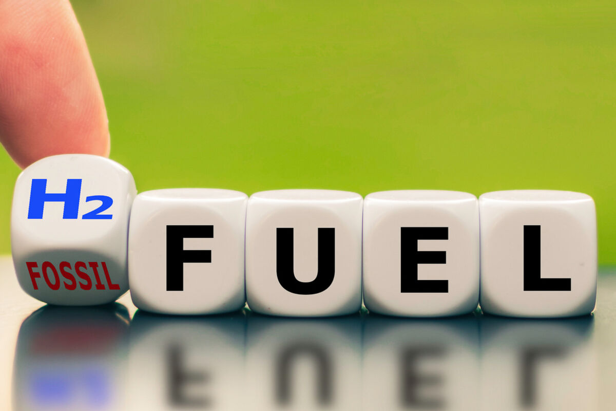Finger flips die from “Fossil” to “H2” in front of dice spelling fuel.