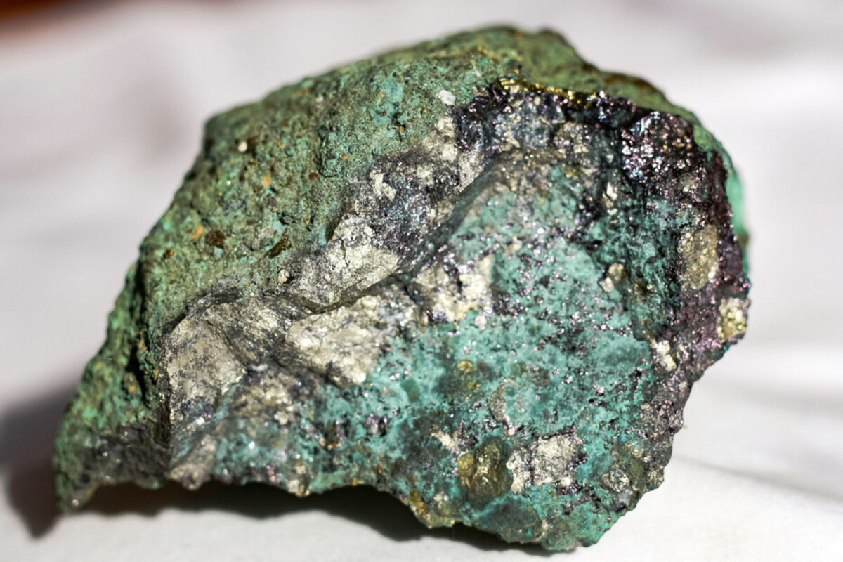 A metallic rock sample stained green from the oxidization of copper.