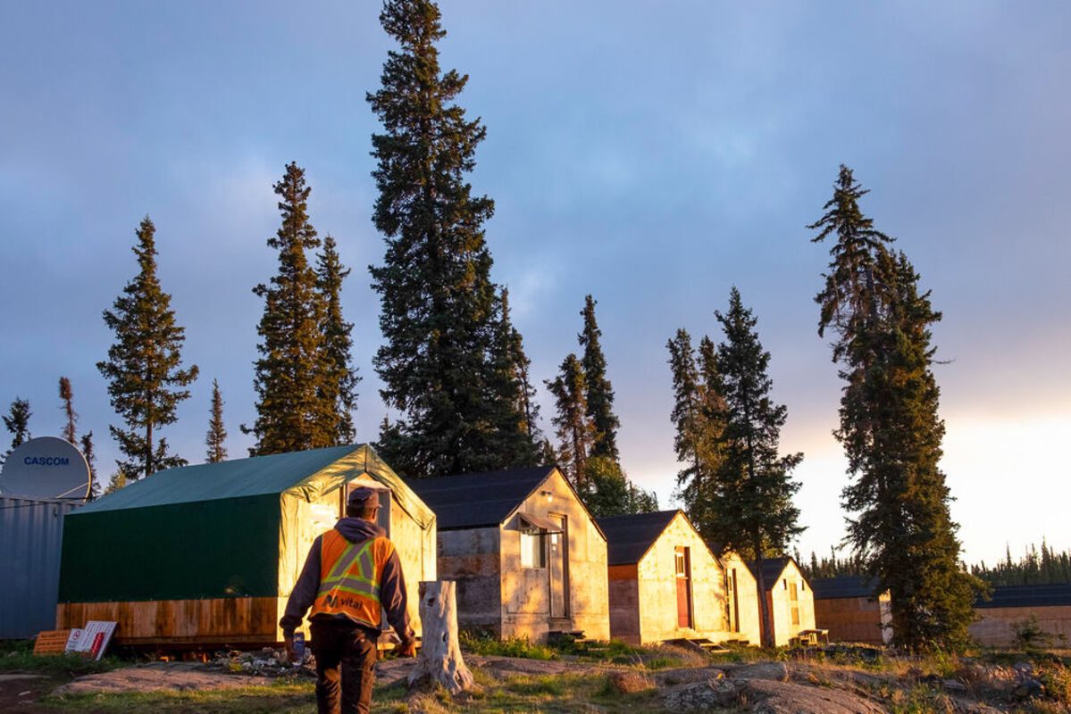 Sunrise brightens tents at Thor Lake camp as Vital Metals worker approaches.