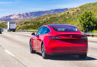 Red Tesla Model 3 electric vehicle traveling a California highway near LA.