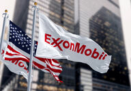 ExxonMobil and American flags flying in front of skyscrapers.