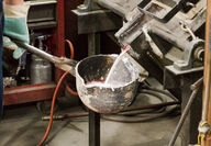 Aluminum-cerium alloy being poured from a furnace into a ladle.