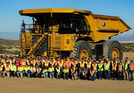 Cat 793 Electric mining truck towers over more than 50 people posed for a photo.