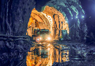 A truck driving into a larger cavern from a tunnel underground.