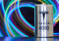 A Tesla 4680 lithium-ion cell for EVs against a background of colorful swirls.