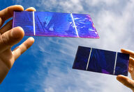Hands holding small thin film solar cell panels.