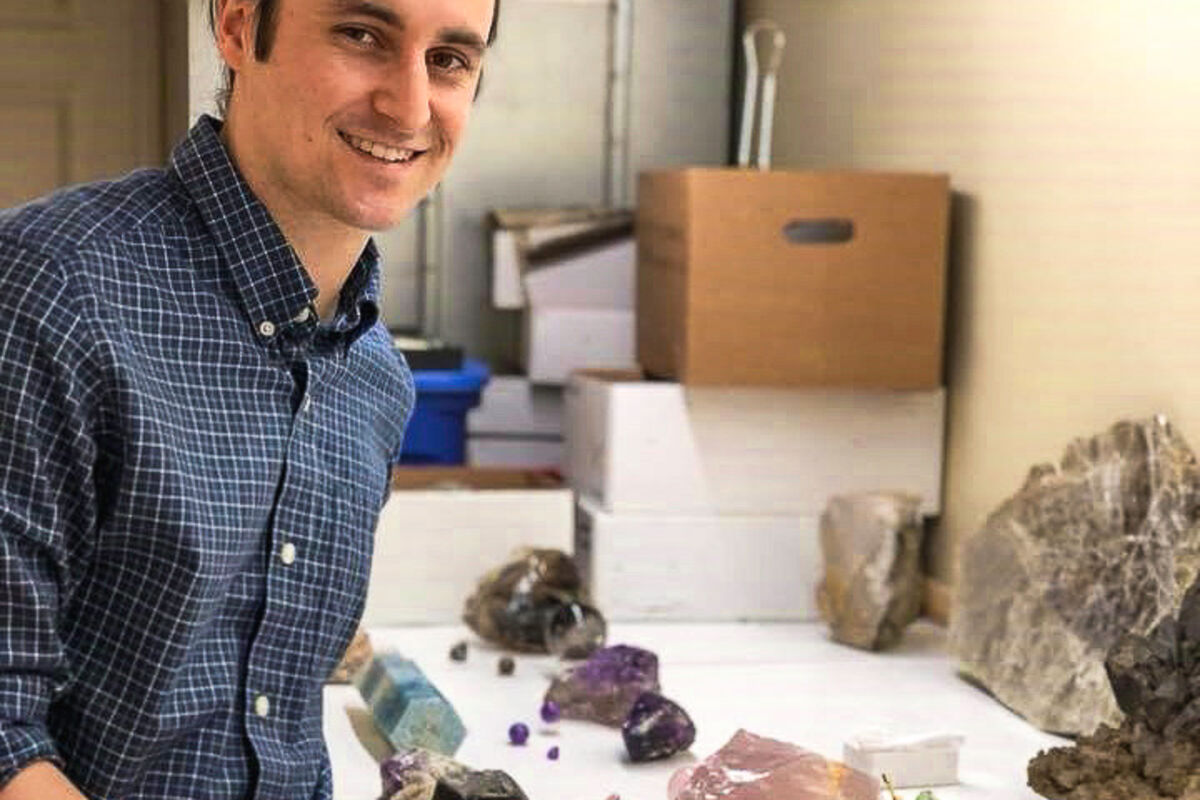 Myles Felch stands in front of several Maine tourmaline specimens.