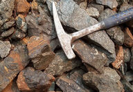A rock hammer laying atop a pile of rare earths enriched carbonatites.