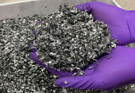 A worker holds a handful of battery metal scrap for recycling.