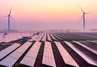 A fuchsia sunrise backdrops wind turbines and reflects off solar panels.