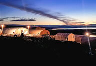 Industrial Quonset tents at Graphite Creek glow at dusk.