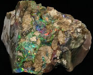 Iridescent rough opal sample within a tan-colored host rock.