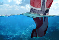 A Norwegian flag dips into the blue waters of the North Sea.