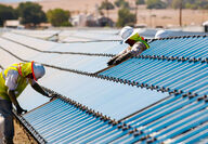 Workers install First Solar thin-film panels in a desert setting.