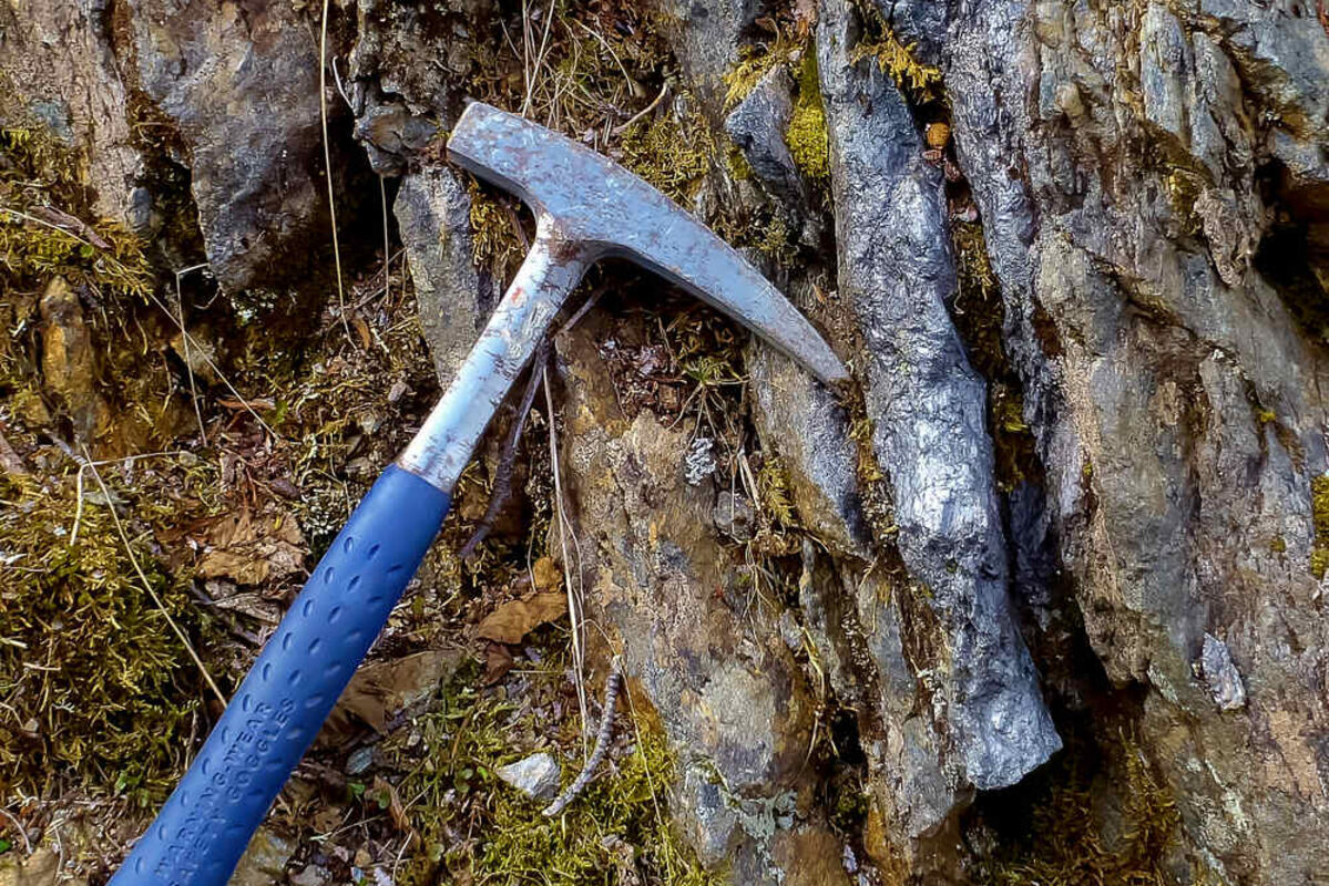 A geologist’s hammer next to lens of graphite at Graphite Creek in Alaska.