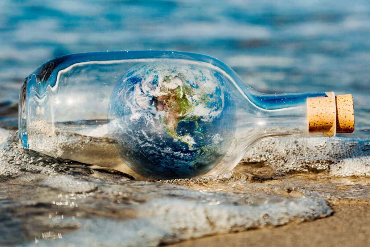 Corked bottle with image of Earth inside as the message washed up on a beach.