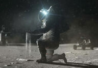 Astronaut in spacesuit pours handful of lunar regolith onto Moon’s surface.