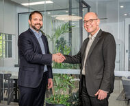 ABB and Perenti executives shaking hands in a modern office environment.